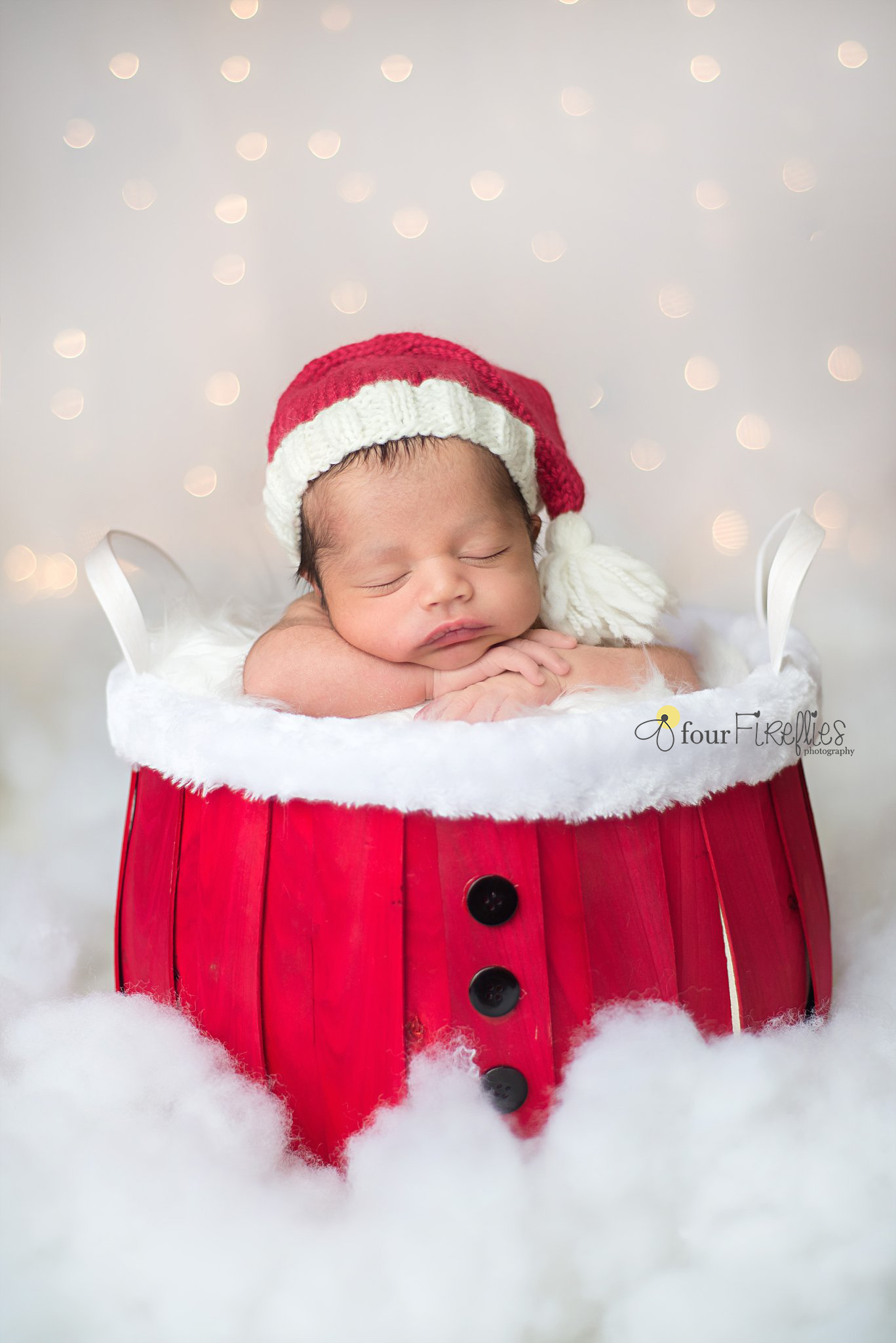 st-louis-newborn-photographer-christmas-baby-in-santa-basket-bucket-hat-with-white-bokeh-background.jpg