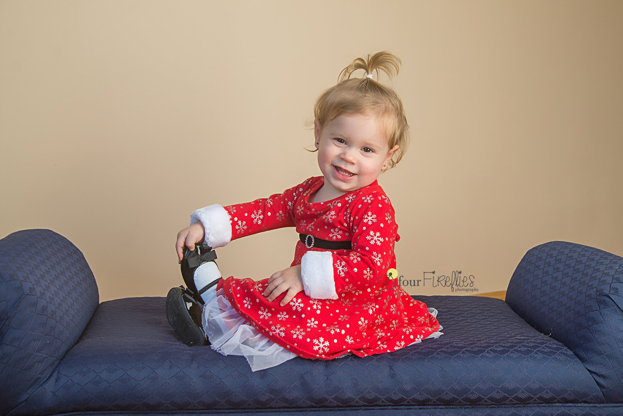 st-louis-photography-studio-girl-in-christmas-dress-holding-feet-on-blue-couch.jpg