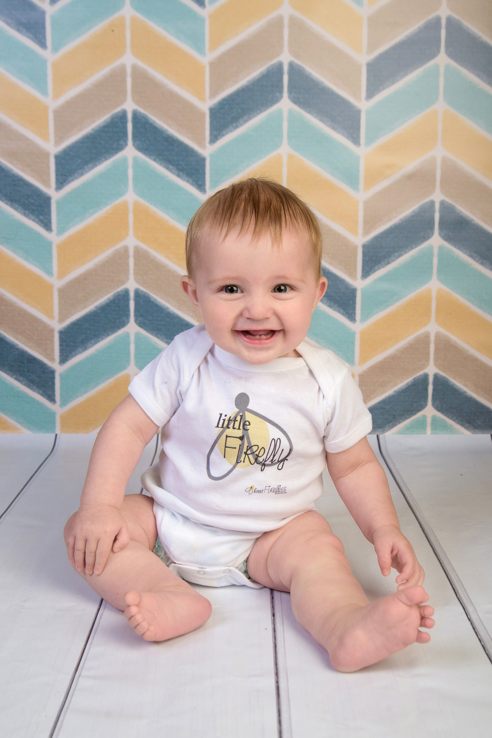 st-louis-photography-studio-six-month-milestone-session-boy-on-yellow-and-blue-weaing-four-fireflies-photography-onsie.jpg