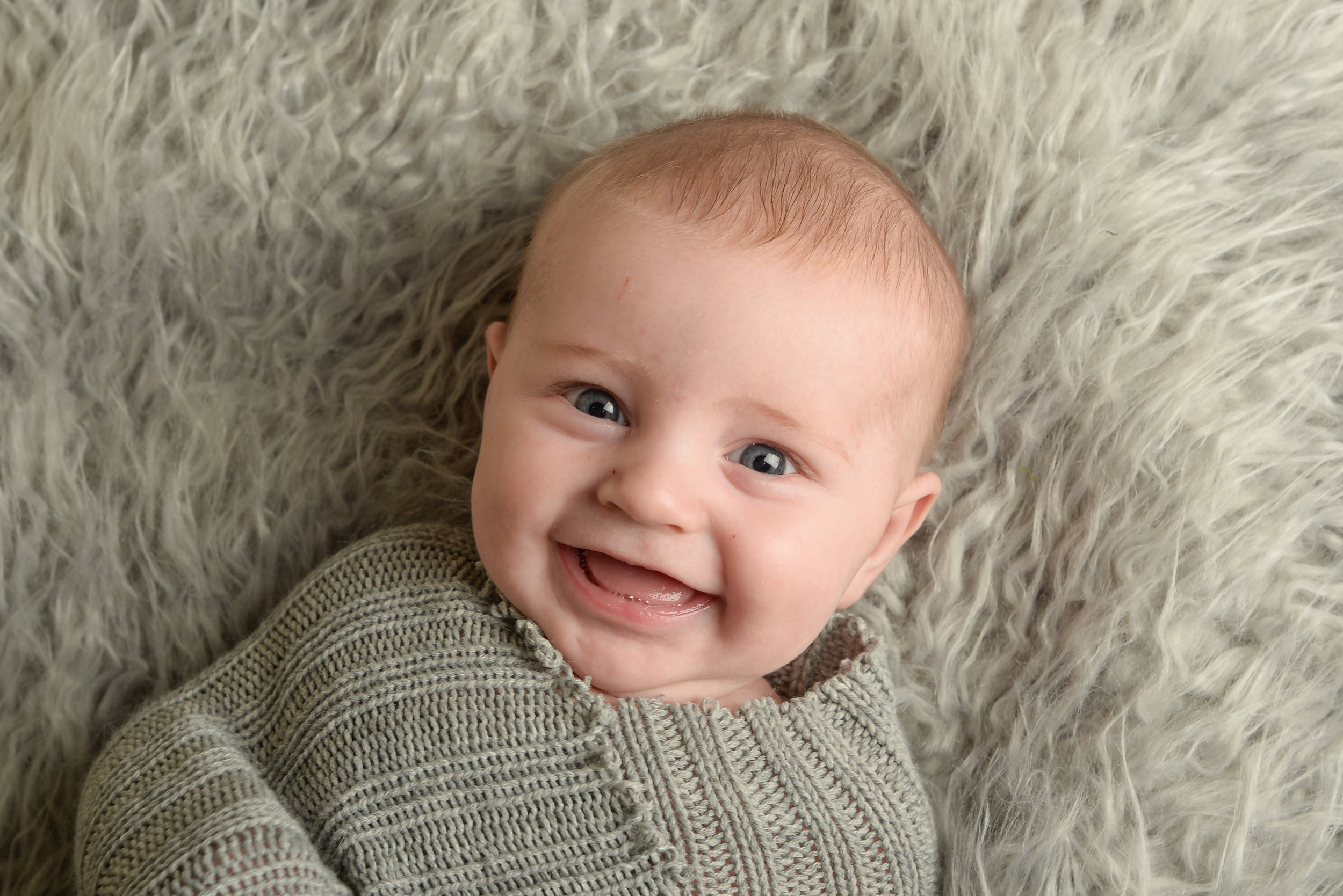 st-louis-photography-studio-three-month-milestone-session-boy-on-gray-fur-with-grey-wrap-smiling.jpg
