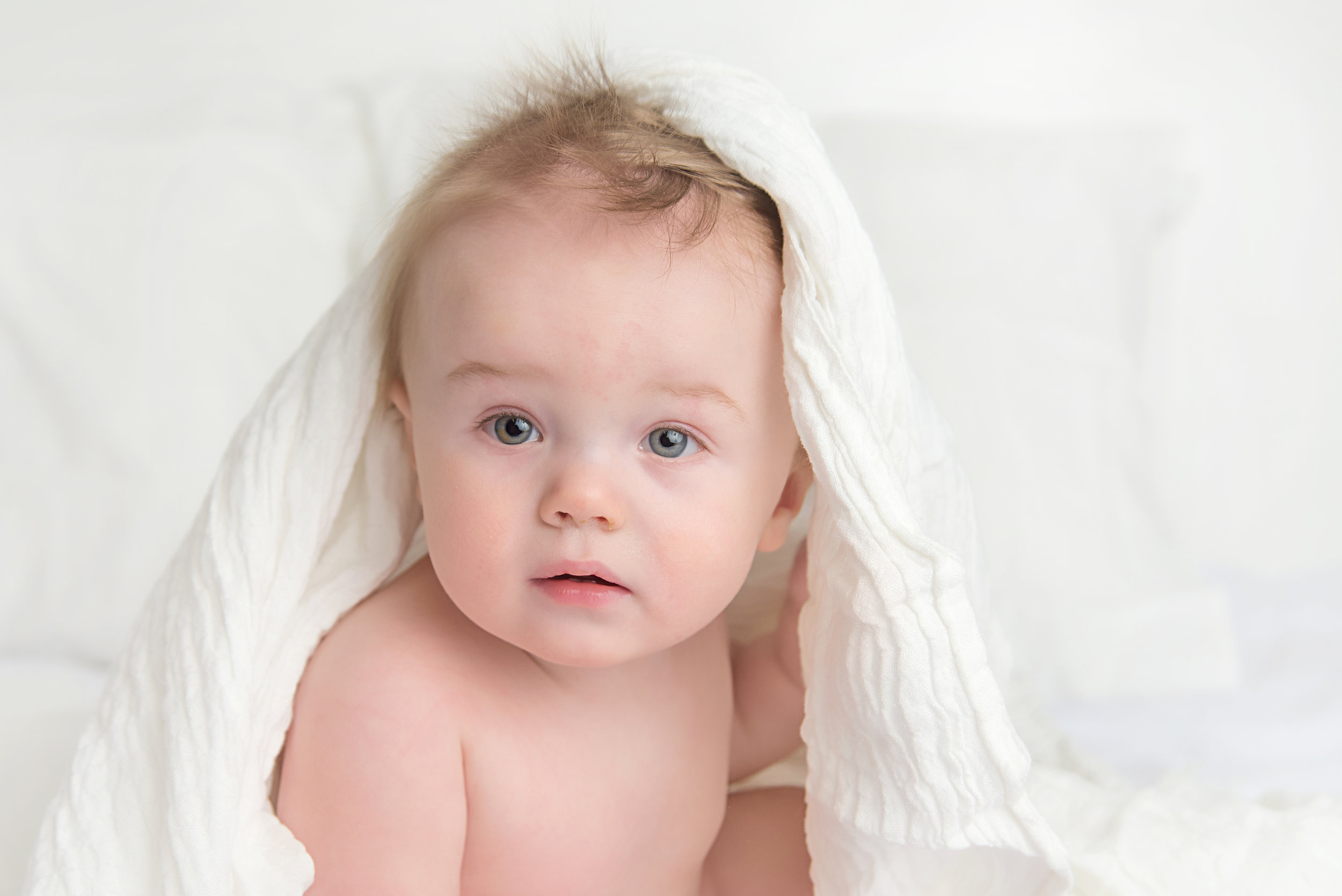 st-louis-baby-photographer-milestone-session-boy-on-white-bed-with-white-blanket-on-his-head.jpg