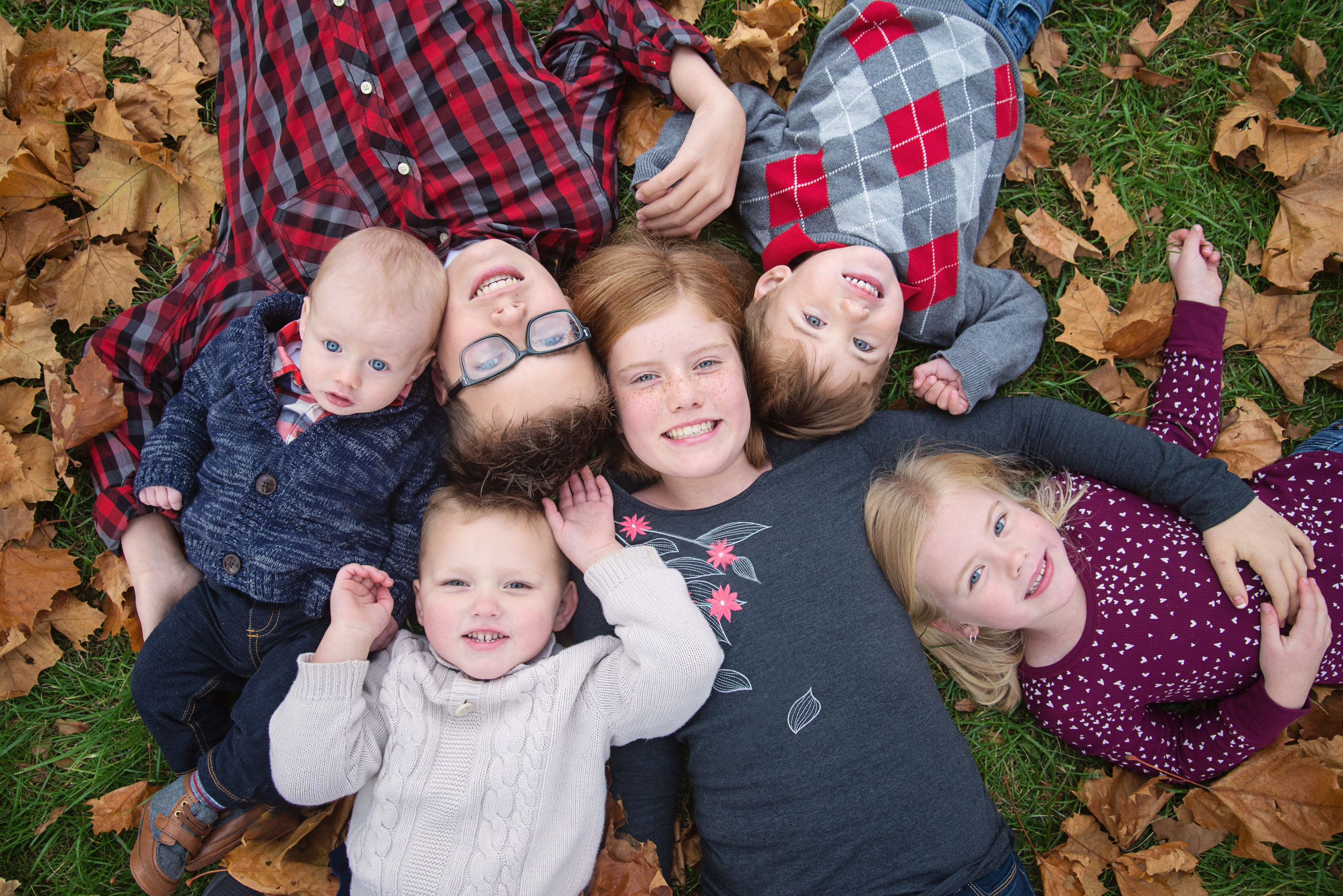 st-louis-family-photographer-six-kids-laying-in-leaves-looking-up-with-heads-together.jpg