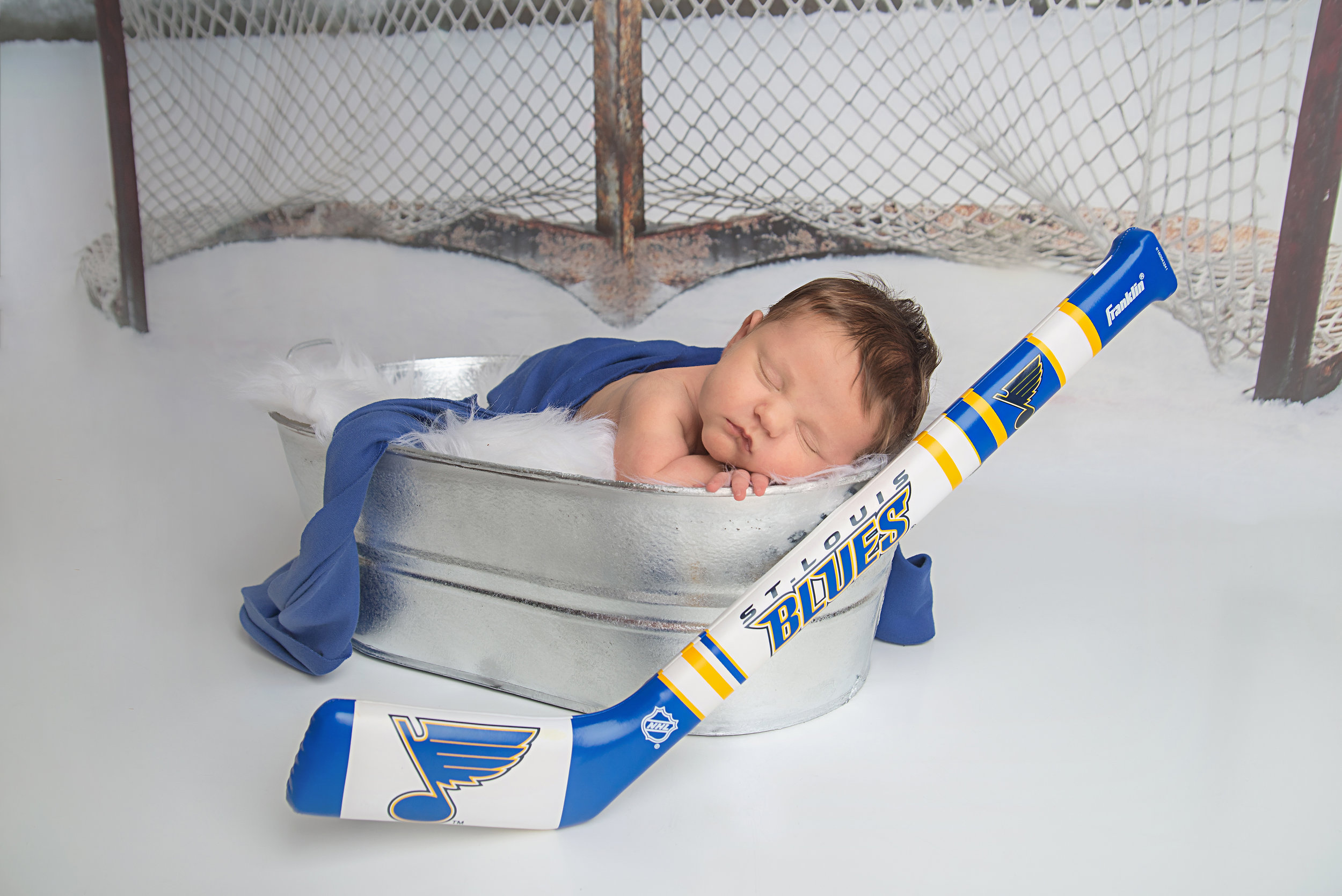 st-louis-newborn-photographer-baby-boy-with-st-louis-blues-hockey-and-hockey-net-backdrop.jpg