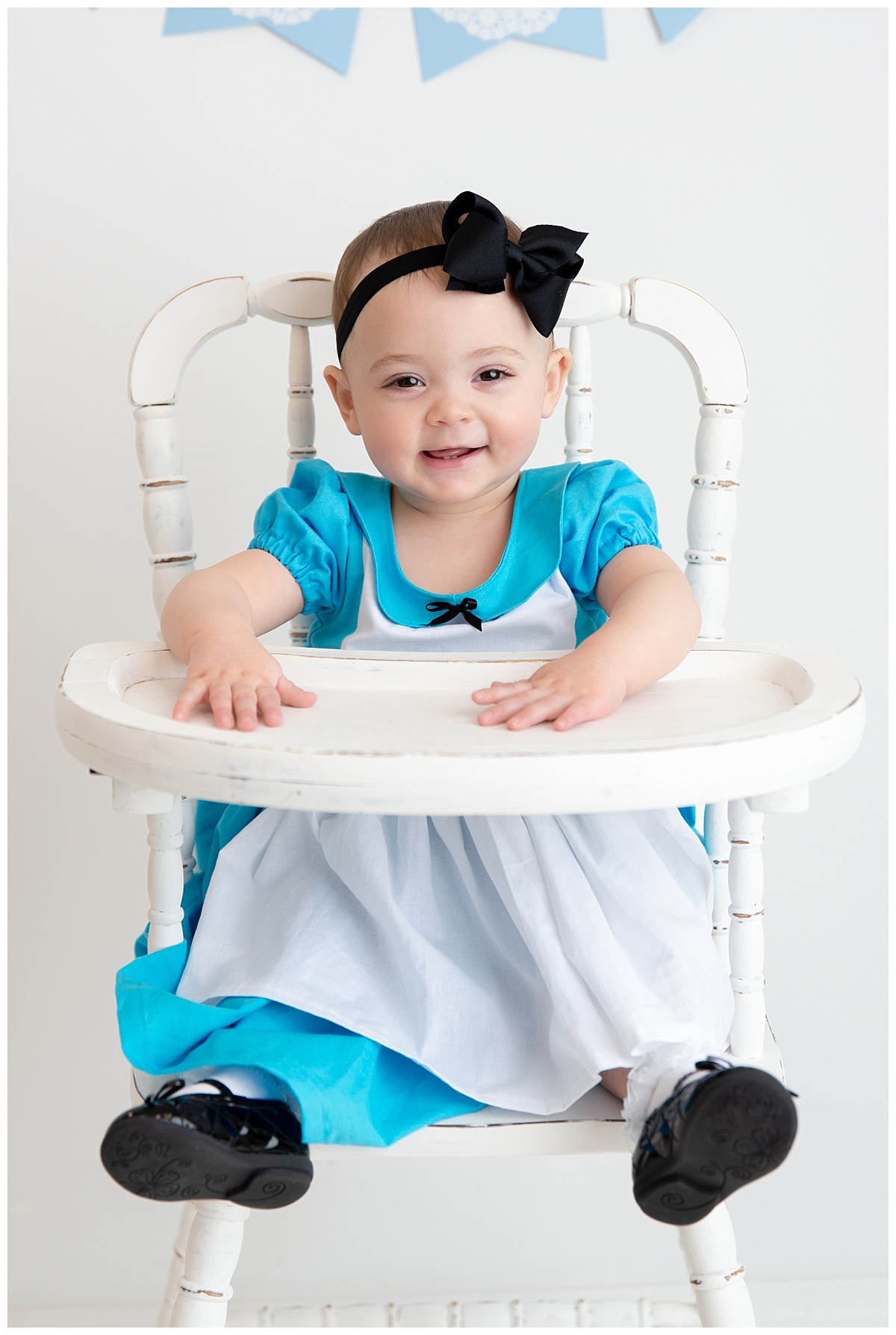 st-louis-birthday-photographer-alice-in-wonderland-dress-baby-girl-sitting-in-white-highchair.jpg