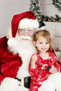 st-louis-santa-experience-santa-sitting-on-couch-with-little-girl-smiling