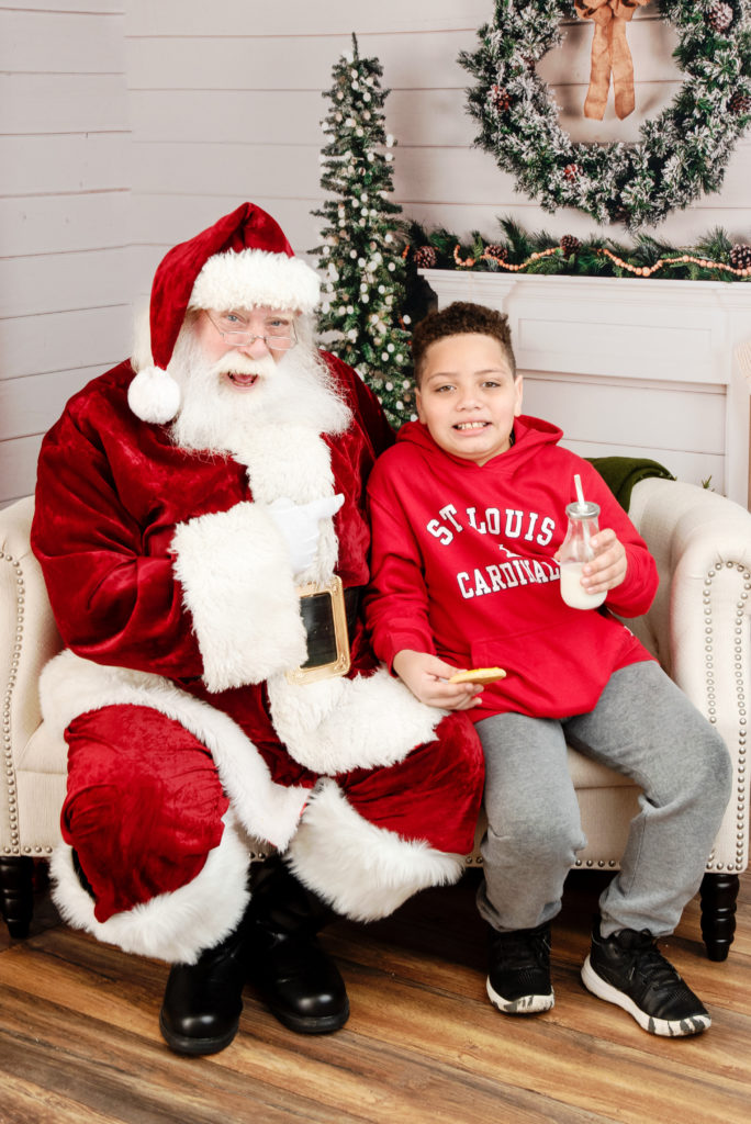 st-louis-santa-experience-santa-sitting-on-couch-with-boy-eating-cookies-and-milk