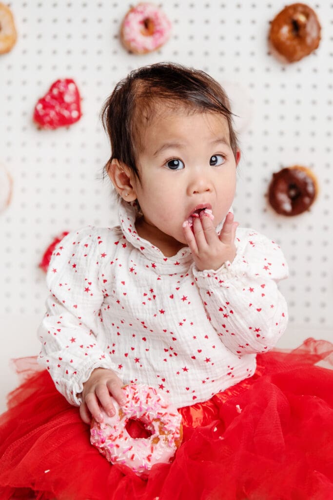 St. Louis Newborn Photographer girl in red and white eating a Valentine's Day donut